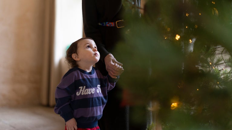 Child looking up at Christmas tree with lights